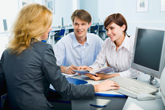 A woman in a suit assisting two other adults with something